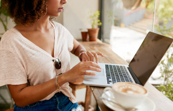 woman typing on a laptop keyboard in café