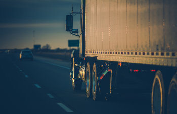 semi truck on the road driving forward in sunset